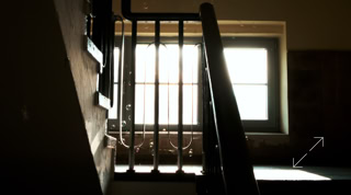 Seifenblasen im Treppenhaus mit Geländer und Fenster im Hintergrund, durch das helles Licht scheint.