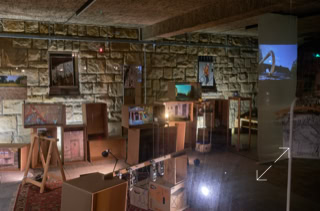 Ein Raum mit Steinwänden, mehreren Bildschirmen, Kartons und Projektoren, die verschiedene Bilder anzeigen.